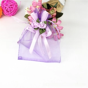 Detail of purple organza gift bag with ribbon bow and small faux rose floral decor