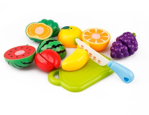 Primo piano di frutta giocattolo colorata in plastica e tagliere per set da cucina.