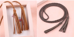 Close-up of woven suede waist ropes in brown and dark grey with elegant tassel details