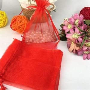 Close-up of red organza drawstring gift bag with ribbon and iridescent beads inside