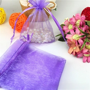 Detailed view of purple organza gift bags with white pearls and satin ribbon drawstring