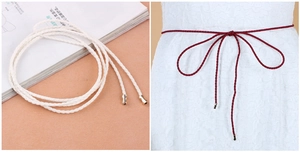 Detail of woven waist belt with metal tassels in white and burgundy on a lace dress