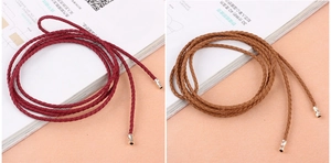 Close-up of thin braided rope belts in red and brown with gold metal end caps
