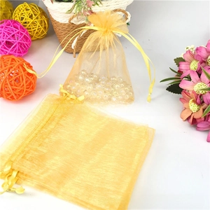 Detail of golden organza drawstring pouch filled with pearls for gift packaging