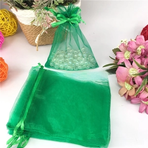 Close-up of green organza drawstring gift bags with translucent mesh and white pearl beads
