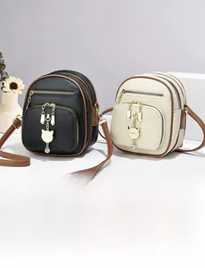 Detail van lederen crossbodytassen met gouden uil-bedels en bruine randafwerking