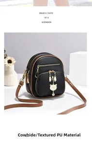 Detail van de zwarte PU-lederen tas met gouden kattenhanger en bruine afwerkingsrand