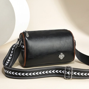 Minimalistische schwarze Zylindertasche mit Kleeblatt-Logo und gewelltem breitem Gurt