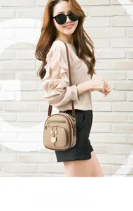 Detail van de kaki lederen mini crossbody tas met gouden kattenhanger en franjes
