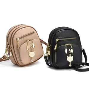 Detail van de schattige gouden kattenhanger op de mini crossbodytas met litchi-textuur