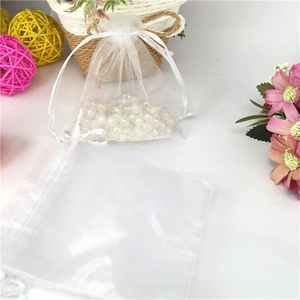 White organza drawstring bag with pearls inside, shown with flowers and rattan balls