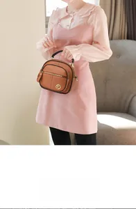 Dettaglio borsa in pelle marrone con logo K dorato, grana litchi e nappa decorativa
