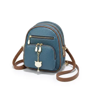 Detail van leren handtas met lychee-patroon, gouden kat en kristallen hanger