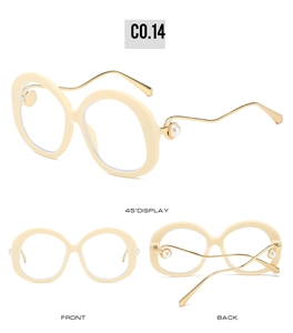 Detail of cream oval sunglasses with wave-shaped gold metal temples and pearl accents