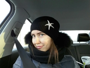 Detail view of a black knitted winter hat featuring a sparkling rhinestone starfish charm