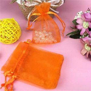 Detail of orange organza drawstring bag showing semi-transparent mesh texture with pearls