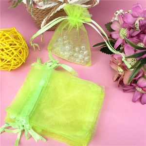 Close-up of lime green organza drawstring gift bags with white pearl accessories inside