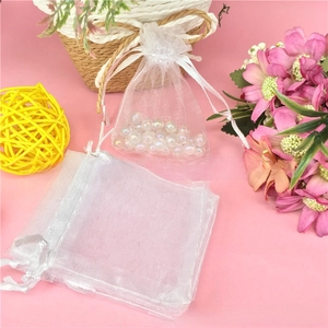 Detailed view of white organza drawstring gift bags filled with decorative pearls