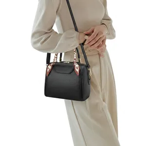Close-up of premium black lychee-textured faux leather handbag with a floral silk scarf handle