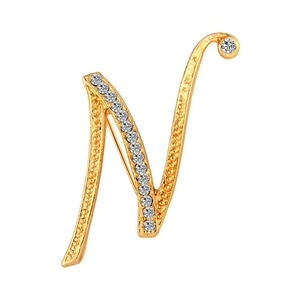 Macro shot of gold letter N brooch with sparkling crystals on a clean white background