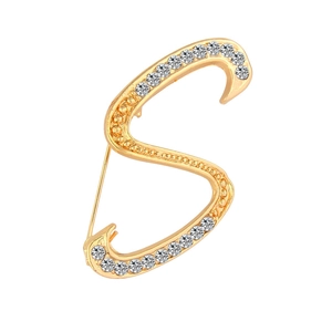 Close-up of golden S-shaped brooch with sparkling rhinestones and secure back pin
