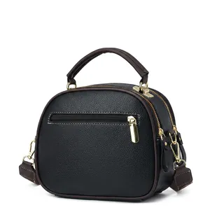 Dettaglio della borsa in pelle nera con tracolla jacquard marrone a fiori