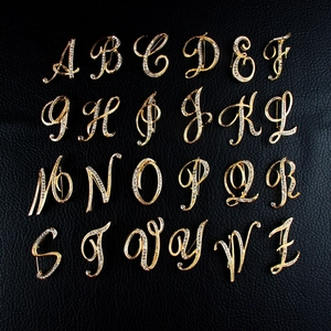 Detailed set of 26 golden alphabet brooches with clear rhinestones on black leather