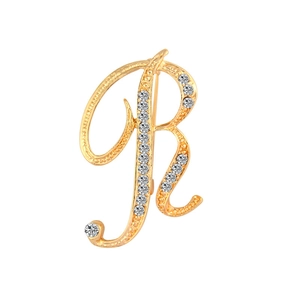 Detailed close-up of a gold-toned R-shaped brooch featuring sparkling crystal rhinestones