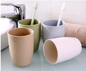 Detail view of four matte plastic mouthwash cups in beige, green, grey, and white colors