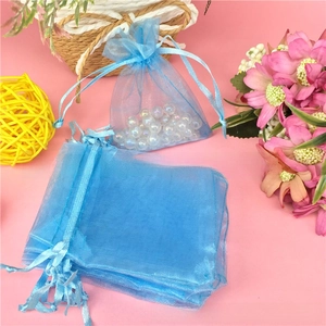 Blue organza drawstring gift bag with gold snowflake pattern and pearl beads inside