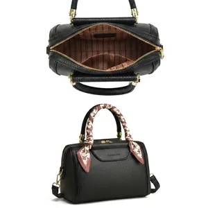Detail of black lychee leather Boston bag with houndstooth silk scarf on handle