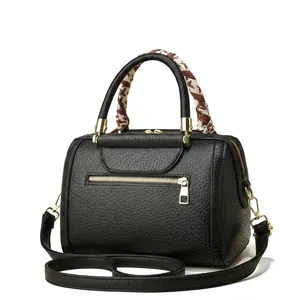 Side view of black lychee grain Boston bag with geometric silk scarf and gold hardware
