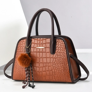 Braune Handtasche mit Krokodilmuster, Goldverschluss und Plüsch-Anhänger auf Weiß