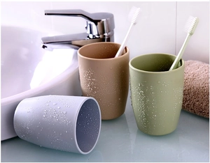 Close-up of minimalist brown, green, and grey plastic tooth mugs with realistic water drops