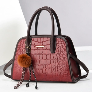 Dunkelrote Handtasche mit Krokodilprägung, braunen Griffen und goldenen Metallakzenten