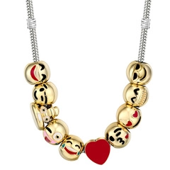 Detail of silver snake chain bracelet featuring gold emoji beads and a red heart pendant