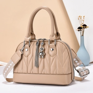 Beige V-quilted shell handbag with woven strap and bear charm in a lifestyle setting