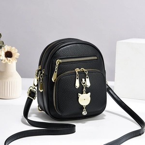 Minimalistische zwarte kunstlederen crossbodytas met kattenhanger en gouden ritsen