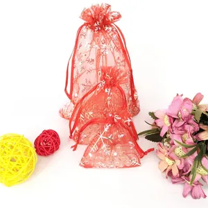 Detail of red organza Christmas gift bags with snowflake prints and drawstring closure