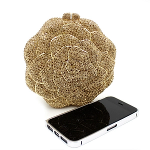 Golden rose-shaped crystal clutch bag next to a phone showing size proportions