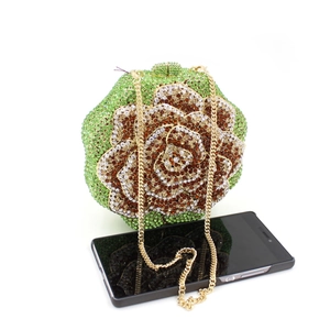 Detailed view of flower-shaped evening bag featuring green rhinestones and metal chain