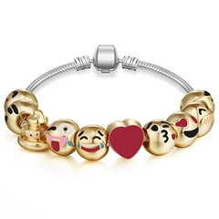 Detail of silver snake chain bracelet with golden emoji beads and a red heart charm