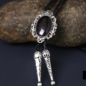 Macro detail of crown bolo tie with black onyx stone and braided leather on rock