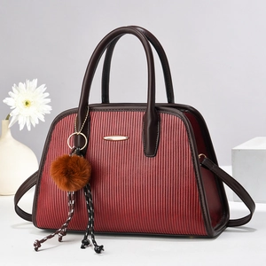 Burgundy striped handbag with gold plaque and brown plush charm in a studio setting