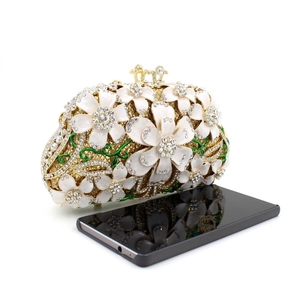 Gold floral evening clutch bag with rhinestones shown next to a smartphone for size