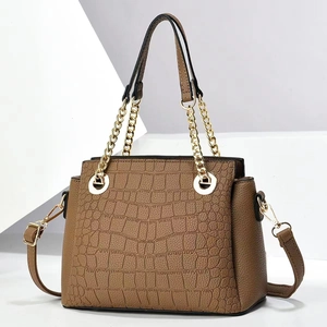 Detailed view of brown crocodile embossed texture handbag with gold chain handle