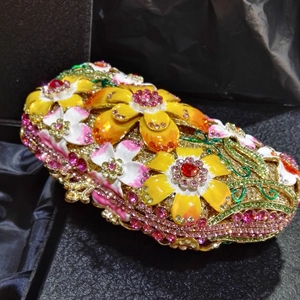 Close-up of golden evening clutch with colorful enamel flowers and sparkling crystals