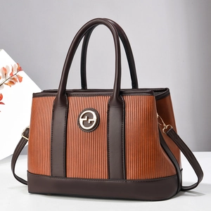 Brown pleated leather tote bag with gold logo and dual handles in a minimalist setting