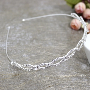 Detail of silver wavy headband with inlaid rhinestones on a textured background