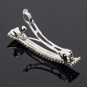Detailed macro view of an open silver metal hair clip with inlaid black rhinestones